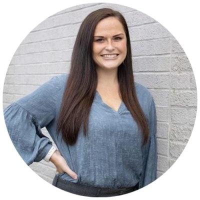 Headshot of a digital marketing specialist smiling outside on a brick wall.