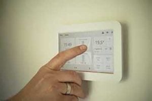 finger touching a thermostat screen in house