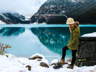 woman outside by a lake with mountains in the background in winter with a flexible printed heater incorporated into her hat and her boots.